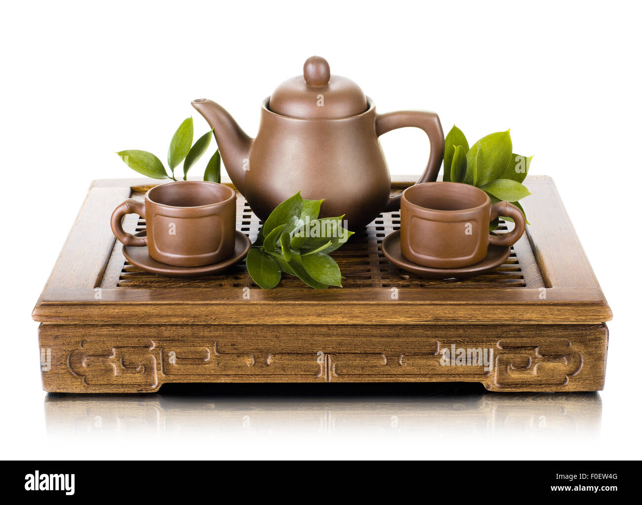 Stillleben mit Ton-Teekanne und Tasse auf hölzerne Untersetzer auf weißem Hintergrund, isoliert Stockfoto