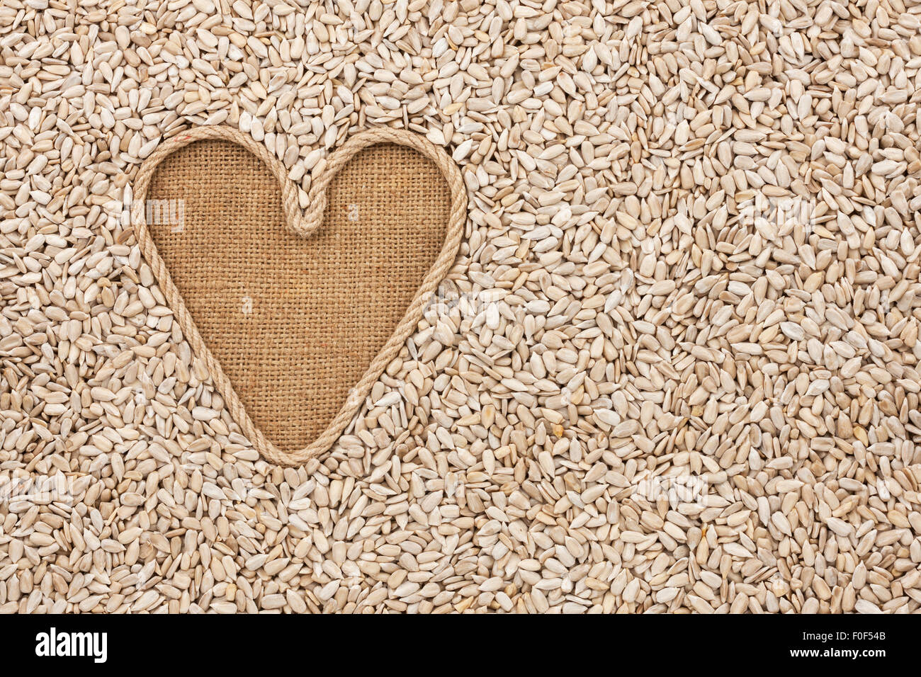 Symbolische Herz des Seils liegt auf Sackleinen und Sonnenblumenkerne, mit Platz für Ihren text Stockfoto