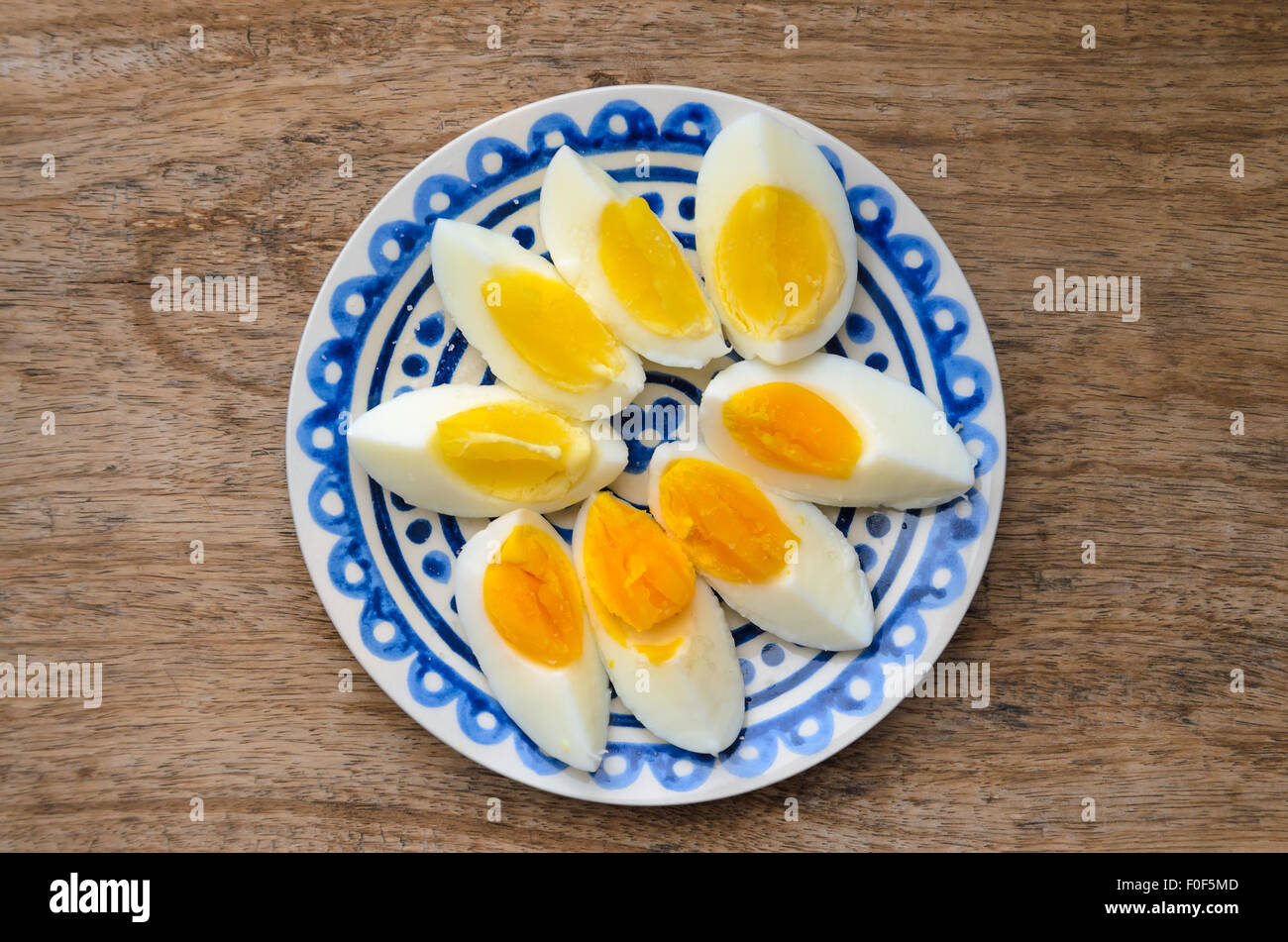 Zwei Farben Eigelb geschnittenen harte gekochte Eiern in einer blauen dekorierten Platte auf Holz Küchentisch. Stockfoto