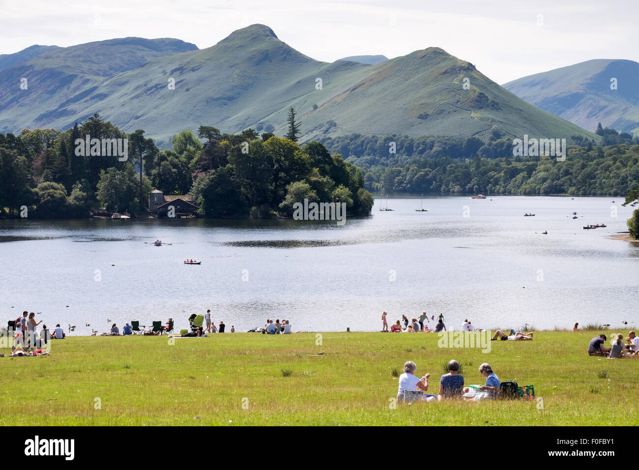Menschen entspannen im Park mit Blick auf Derwentwater und Catbells Fells in der Nähe von Keswick im Lake District, Cumbria, England Stockfoto