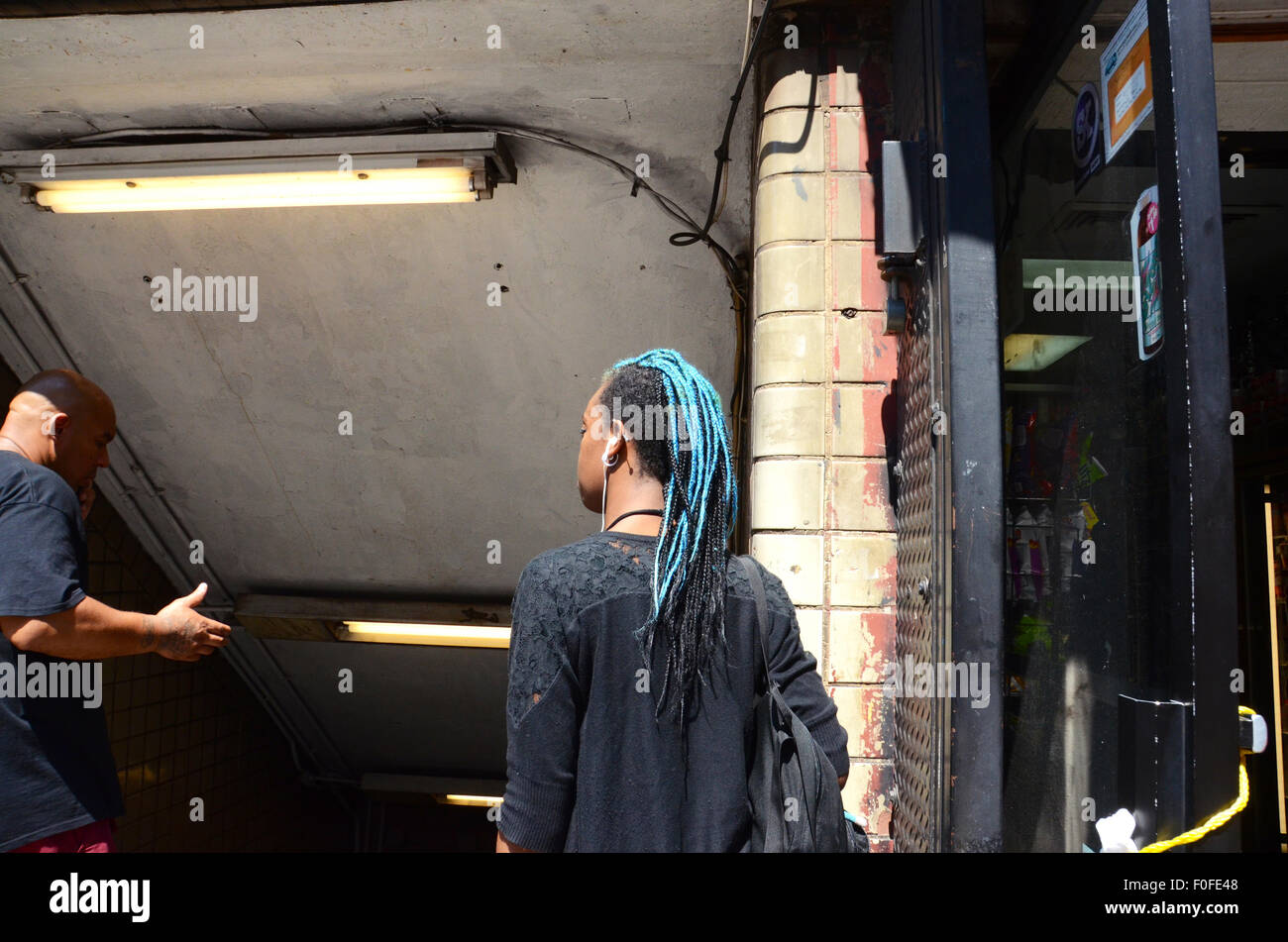 geflochtene blaue Haare schwarze Frau Ohr Telefone Knospen Straßenszene New York Usa Brooklyn Hoyt Schermerhorn u-Bahn A C G Linie Lichtleiste Stockfoto