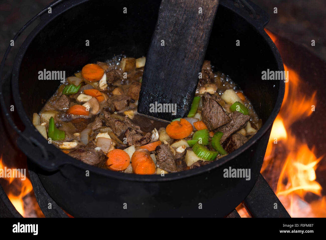 Rindfleisch-Eintopf kochen in einem gusseisernen Dutch Oven über eine offene Lagerfeuer Stockfoto