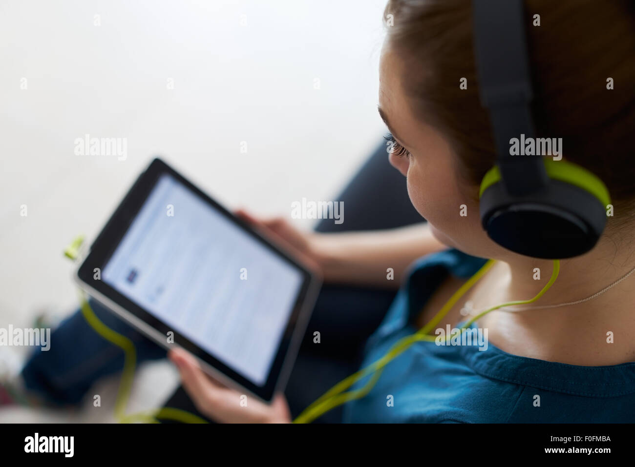 Schöne Frau entspannt auf Sofa und Uhren Podcast auf TabletPC mit grünen großen Kopfhörern hören. Textfreiraum Stockfoto