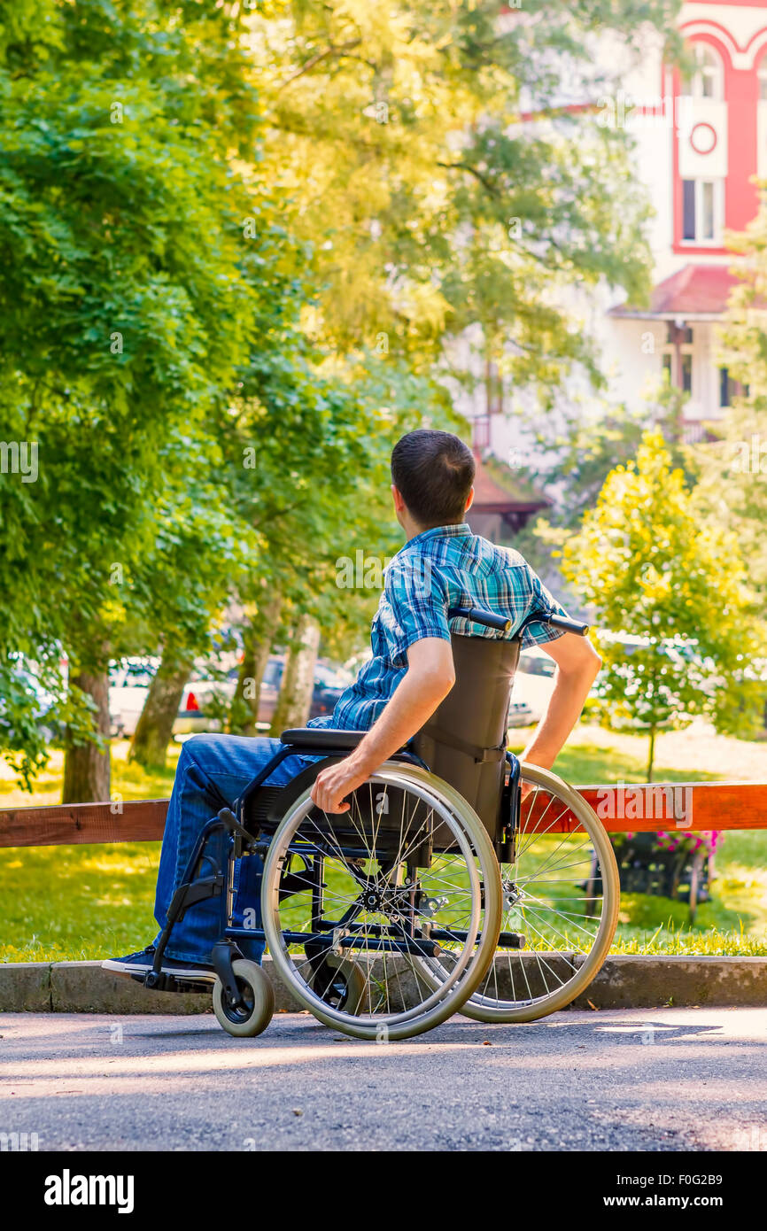 junger Mann im Rollstuhl im Stadtpark Stockfoto