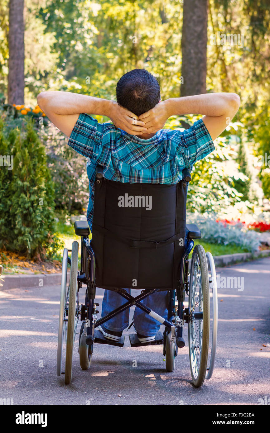 junger Mann im Rollstuhl an der frischen Luft im Stadtpark Stockfoto