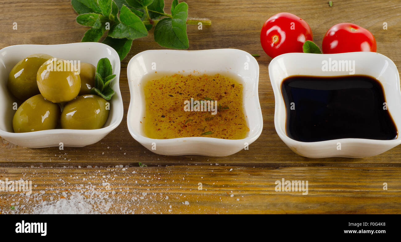 Dressing Zutaten auf einem rustikalen Hintergrund. Olivenöl, Balsamico-Essig, Kräuter, Salz und Pfeffer. Stockfoto