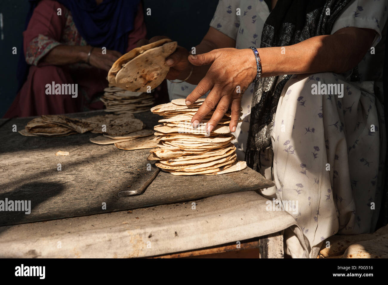 Amritsar, Punjab, Indien. Sri Harmandir Sahib goldenen Tempel. Eine Frau stapelt Roti-Fladen in der freien Küche - Langar - die Zehntausende von Menschen jeden Tag füttert. Stockfoto
