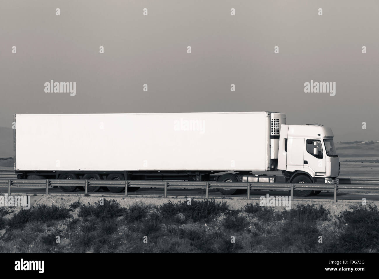 Lange weiße Fracht-LKW auf der Straße mit grauen Himmel, Digital retuschiert und getönten Foto mit Platz für Text und Grafiken. Stockfoto