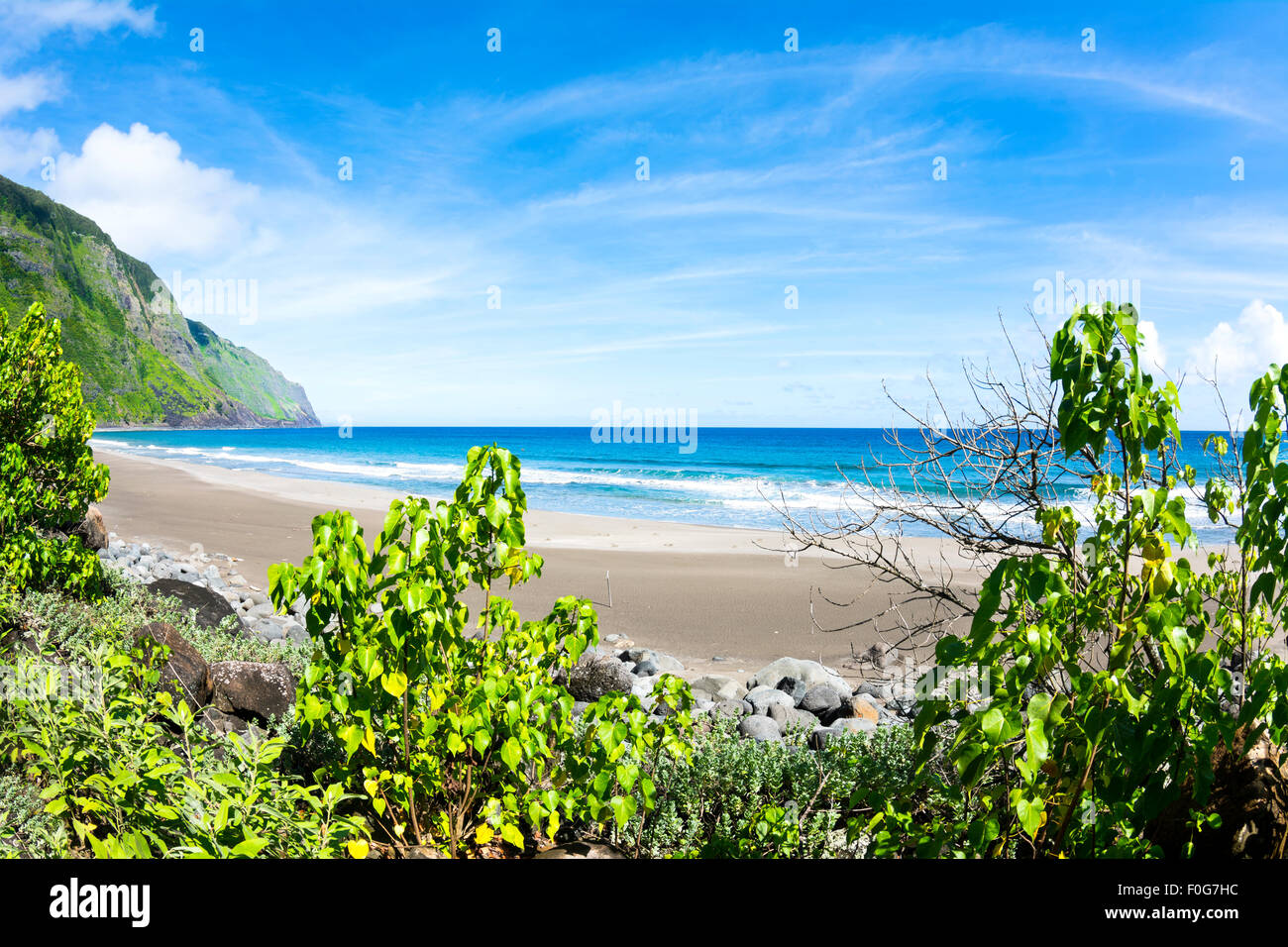Blick auf einen tropischen Strand von der Deckung des lebendigen, grünen Laub Stockfoto