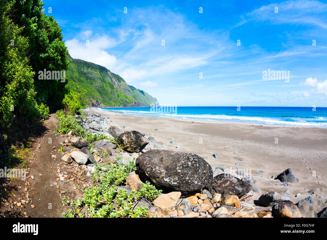 Blick auf einen tropischen Strand in Hawaii mit einer Spur führt in den Berghang Laub Stockfoto