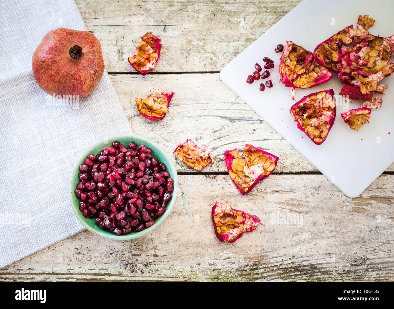 Granatapfel-Frucht, Schale und Samen auf einem rustikalen Tisch Stockfoto