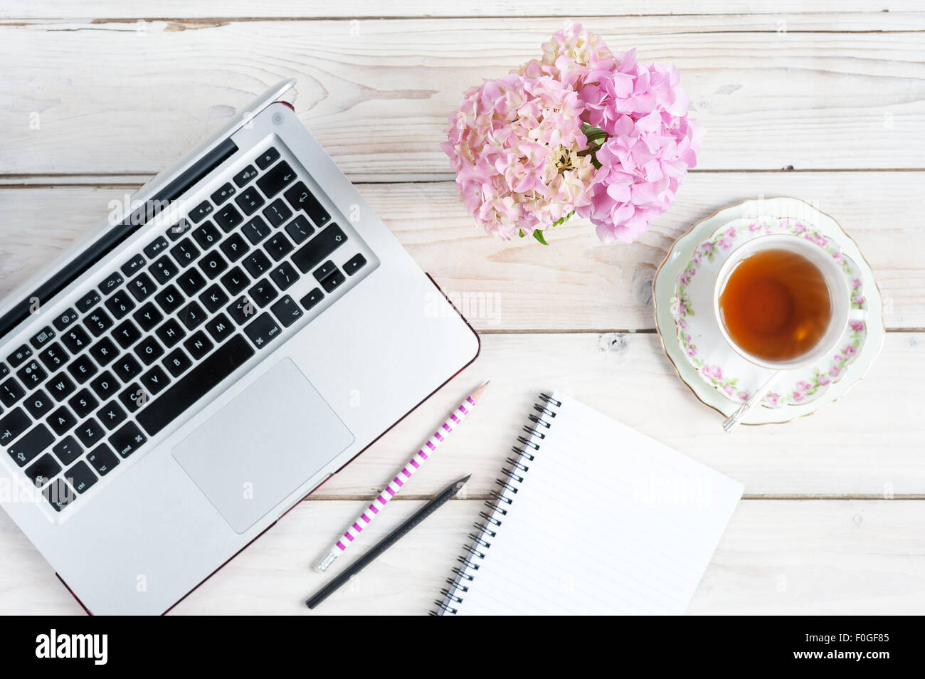 Arbeiten von zu Hause - Laptop, Notebook, Stifte, Tee und Rosen Stockfoto