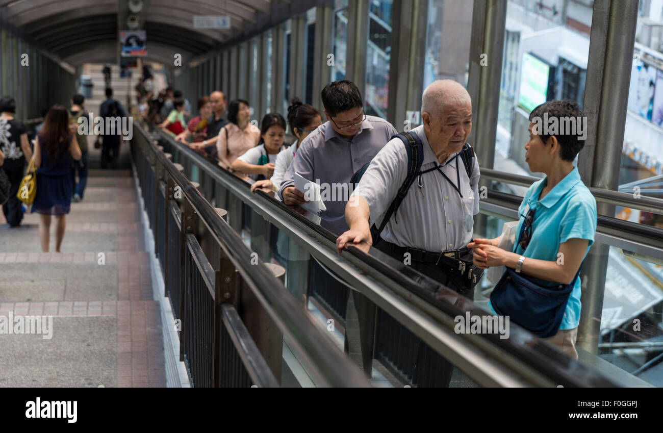 Fußgänger fahren die Mid-Level-Rolltreppen den steilen Hügel des zentralen Bezirk von Hong Kong Island. Anderen hinabsteigen Treppen. Stockfoto