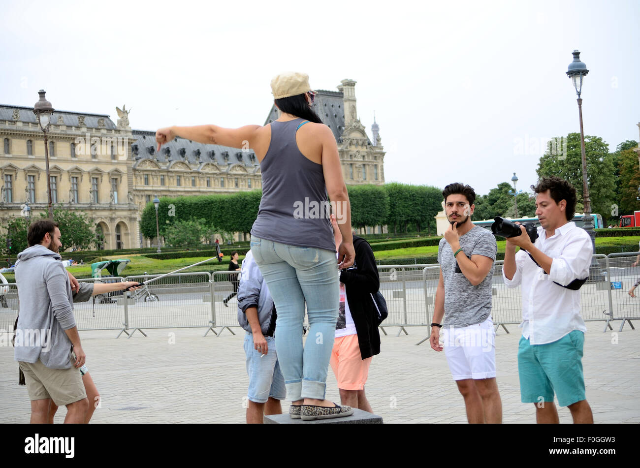Eine junge Dame steht auf einem Podest vor dem Louvre in Paris, für ein Foto zu posieren. Stockfoto
