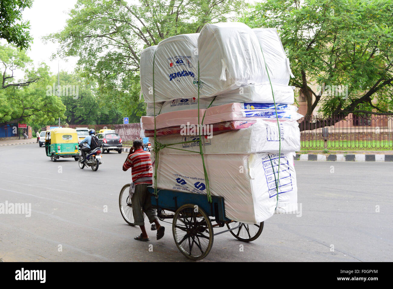 Cycle rickshaw vom Mann mit schweren Gütern in Delhi Indien gezogen Stockfoto