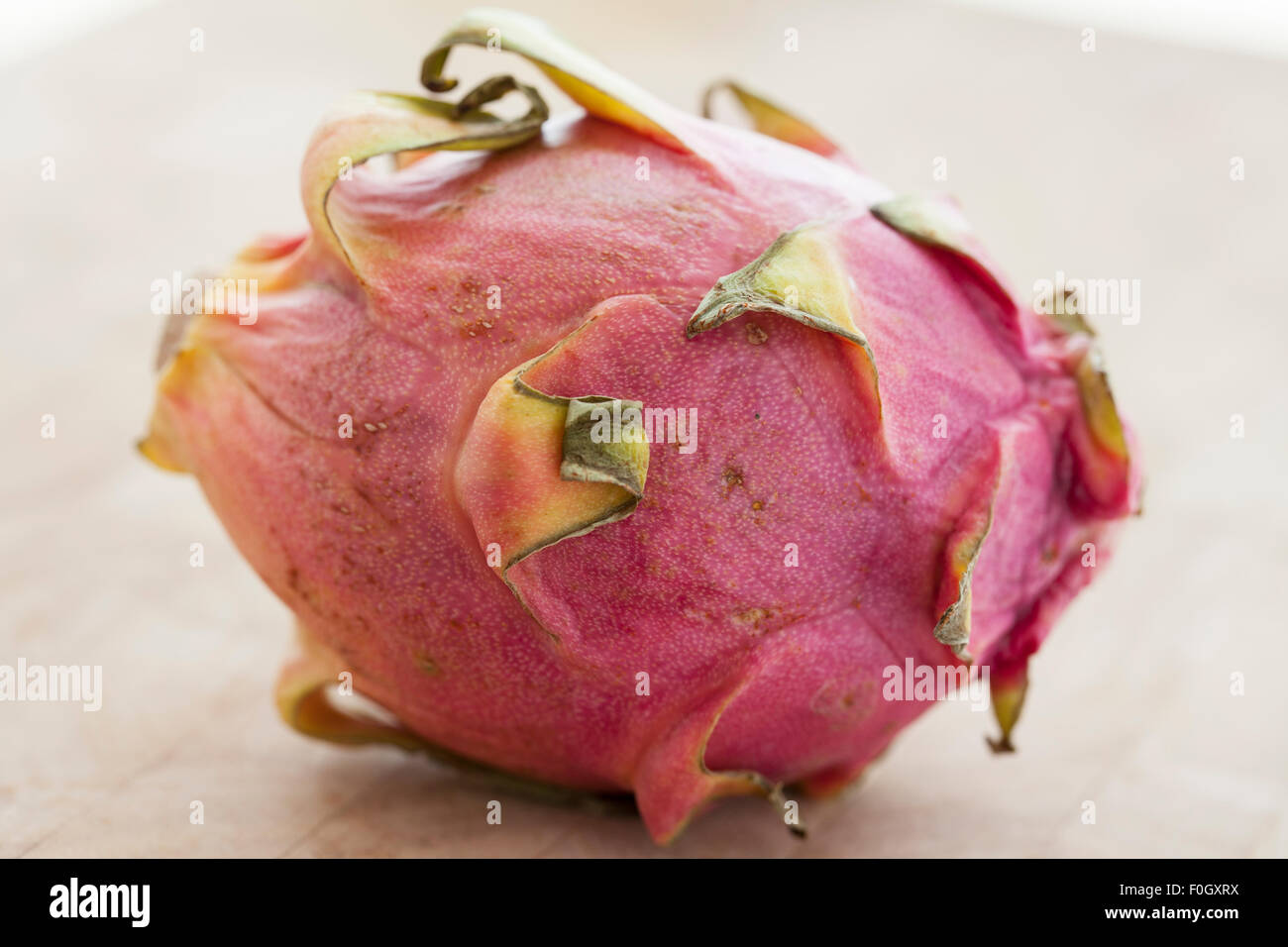 Eine Drachenfrucht oder Pitaya auf einer Holzfläche mit Fensterlicht fotografiert. Stockfoto