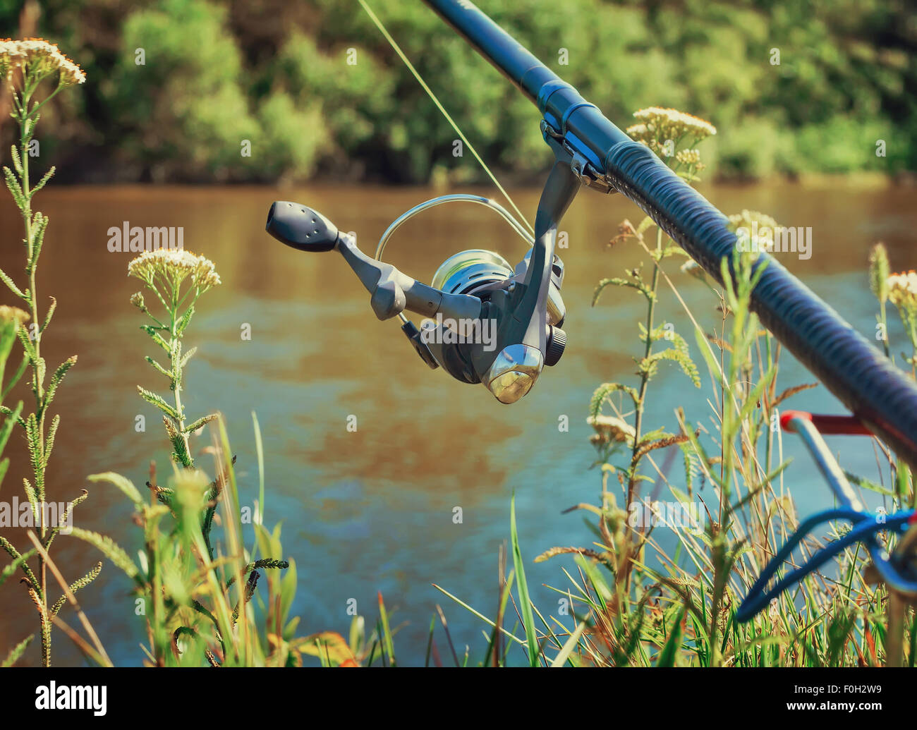An den Ufern des schönen Flusses oberhalb der Wasser-Feeder installiert - Englisch Angelgerät für den Fang von Fischen mit Stockfoto