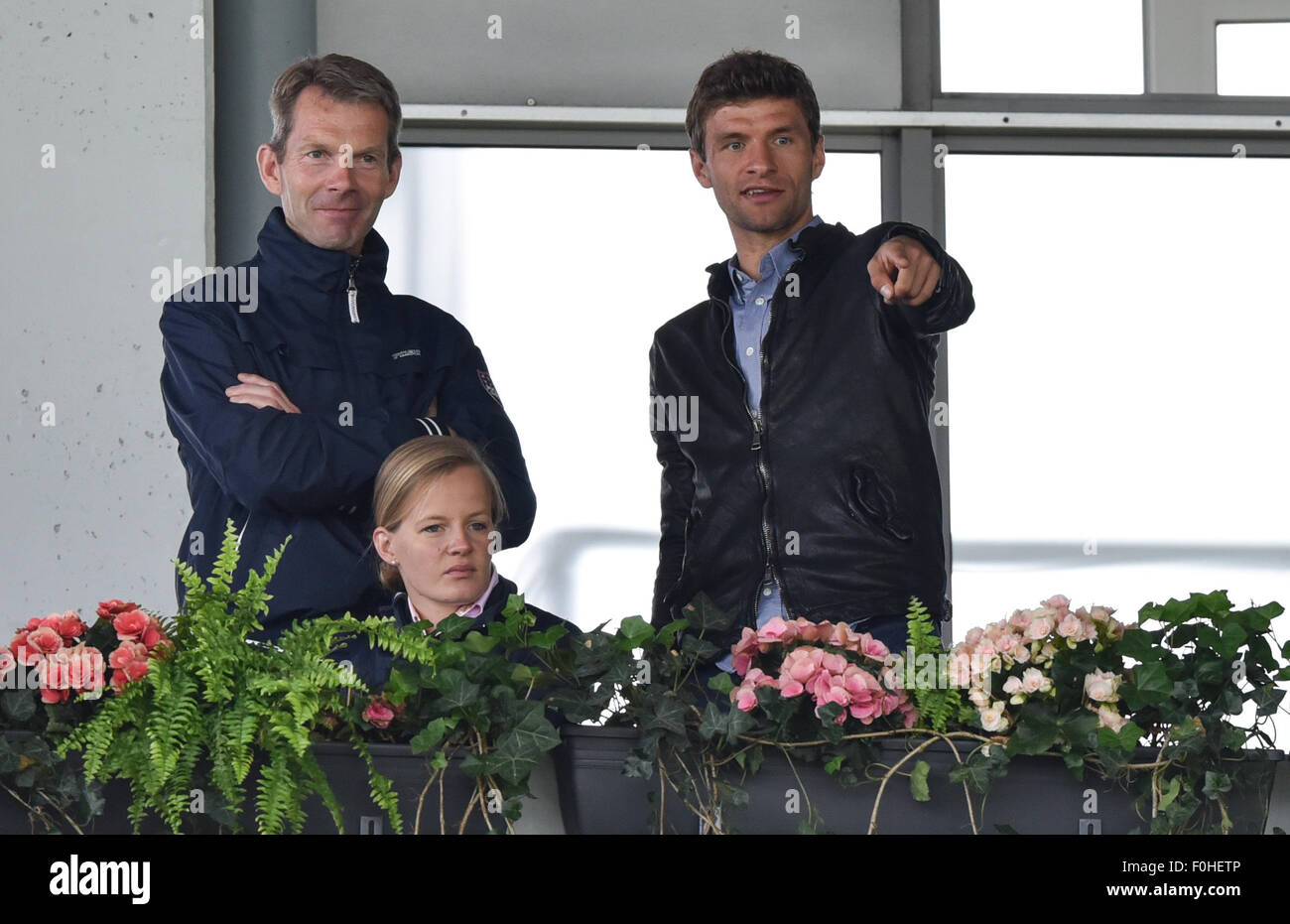 Fußball-Spieler Thomas Müller (R) des FC Bayern München steht auf der Tribüne in der Grand Prix Kür Dressur individuelle Finale während der FEI European Championships in Aachen, Deutschland, 16. August 2015. Foto: Uwe Anspach/dpa Stockfoto