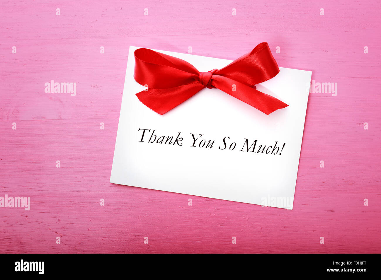 Dankeschön-Karte mit rotem Band auf rosa Holzbrett Stockfoto