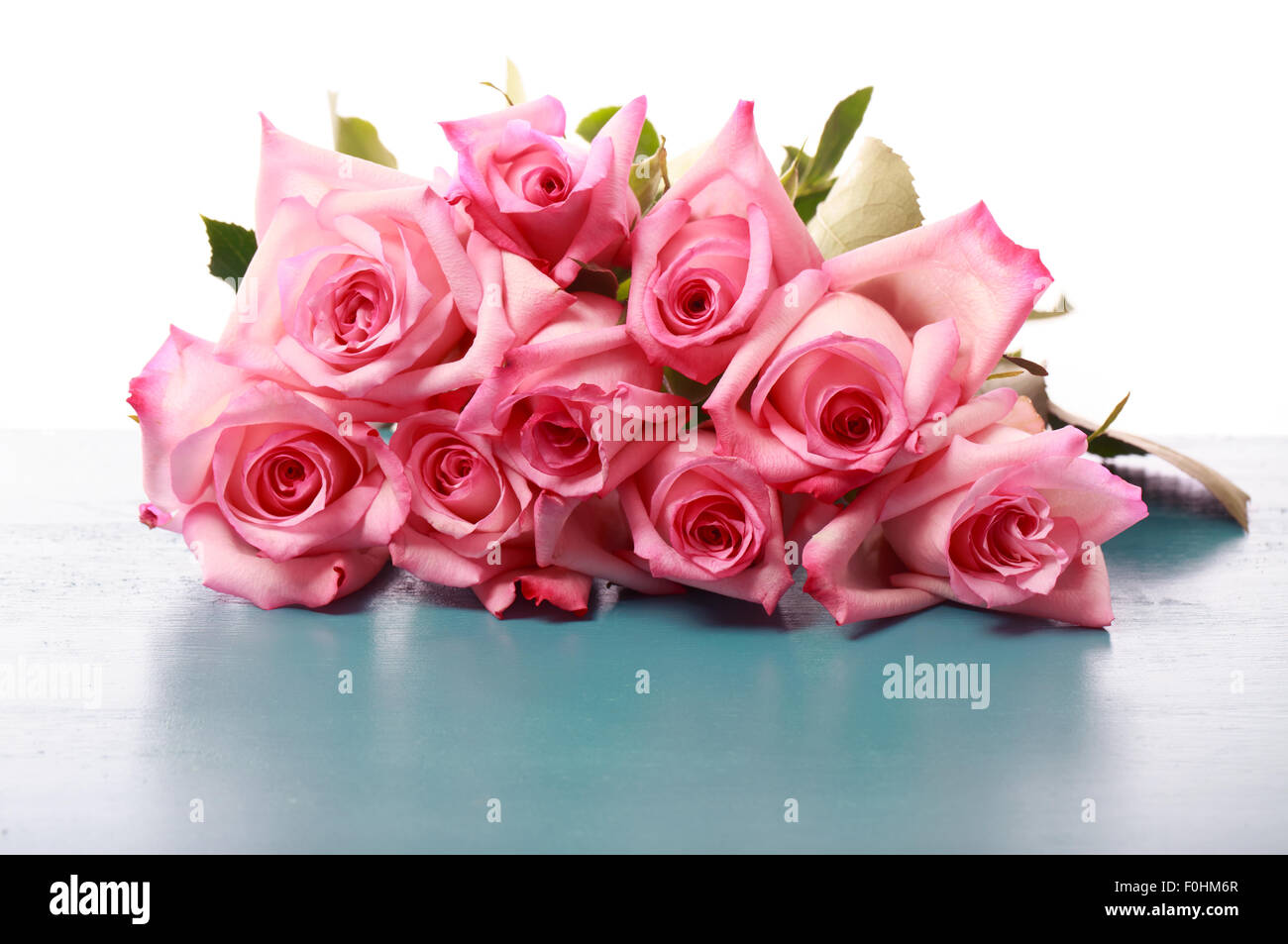 Schöne rosa Rosen auf blauem Holzbrett Stockfoto