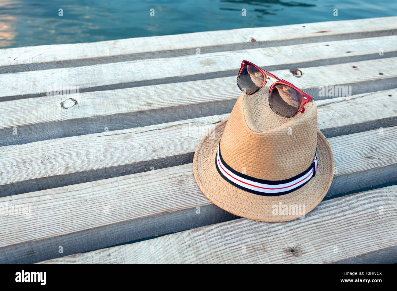 Sonnenbrillen, Flip-flops und Hut auf die hölzerne Struktur im Sommer. Stockfoto