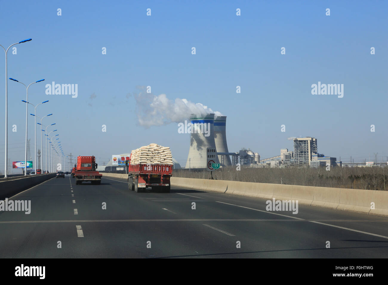 LKW-Verkehr auf der Autobahn verlassen Tianjin Hafen in Richtung Beijing. Zwei Kühltürme sind nördlich der Autobahn S30. Stockfoto