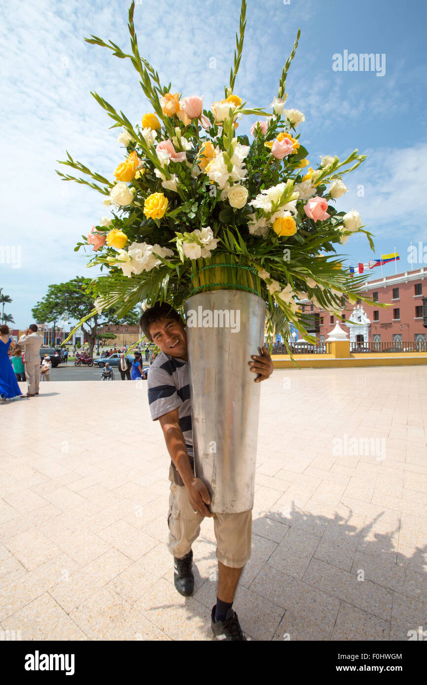 Unbekannten peruanischen Mann hält eine große Vase mit weißen und gelben Rosen außerhalb der Kirche in Trujillo - Peru 2015 Stockfoto