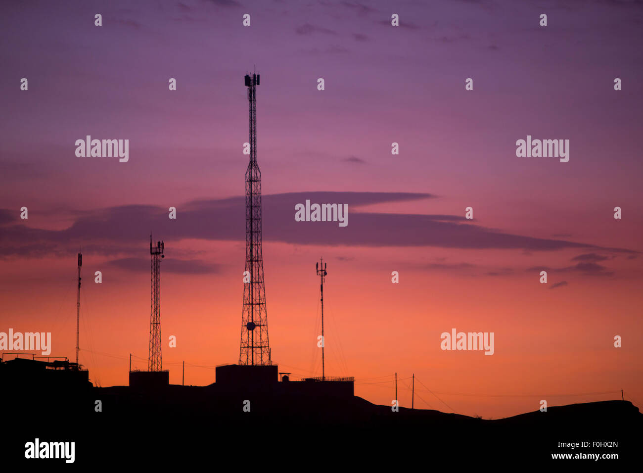 Orange lila Sonnenuntergang mit Silhouette der Telekommunikation Türme und Telefonkabel in Mancora. Peru Stockfoto