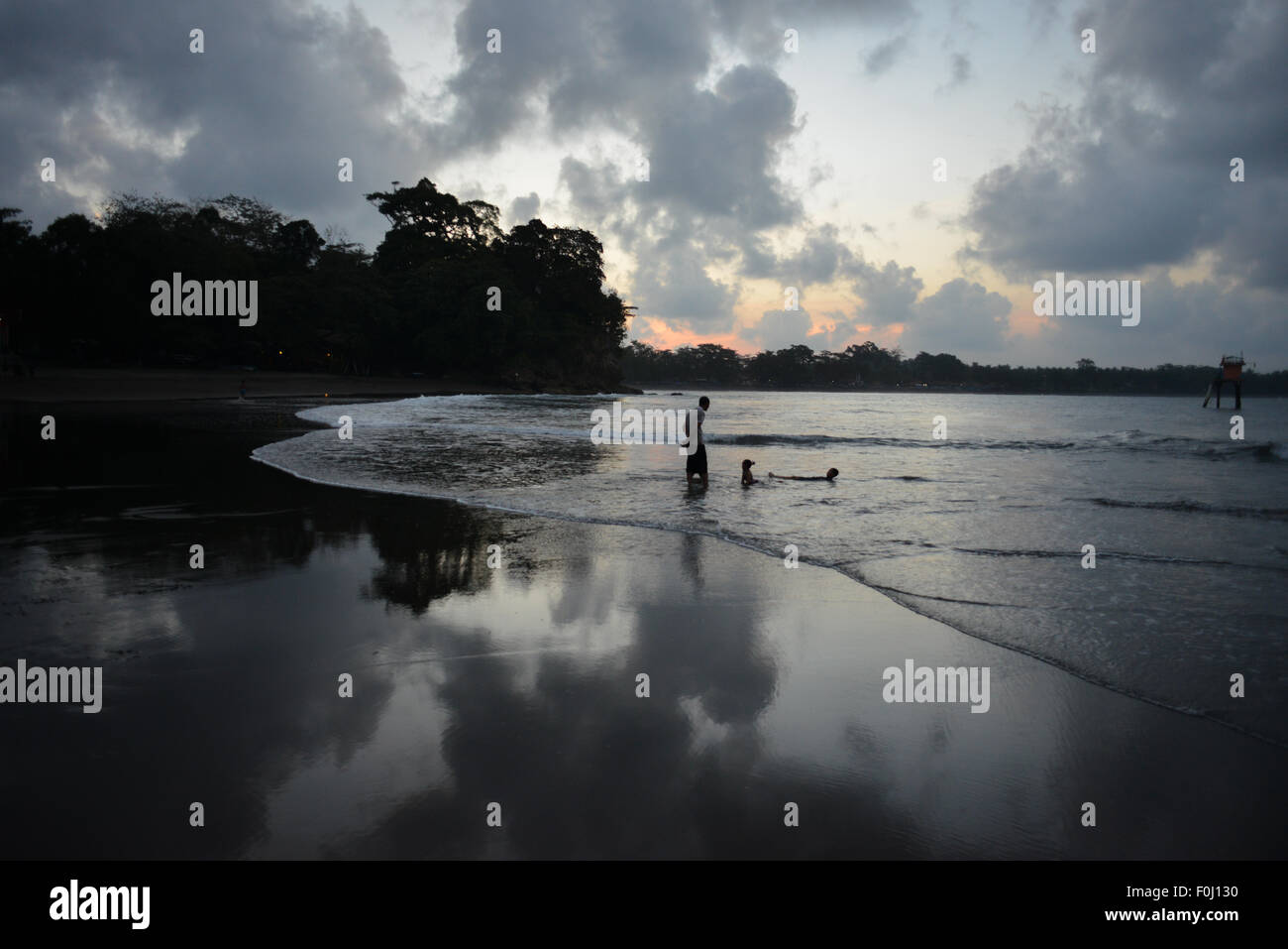 Menschen genießen das Wasser als die Sonne untergeht, am Batukaras Strand in West-Java, Indonesien am 9. August 2015. Stockfoto