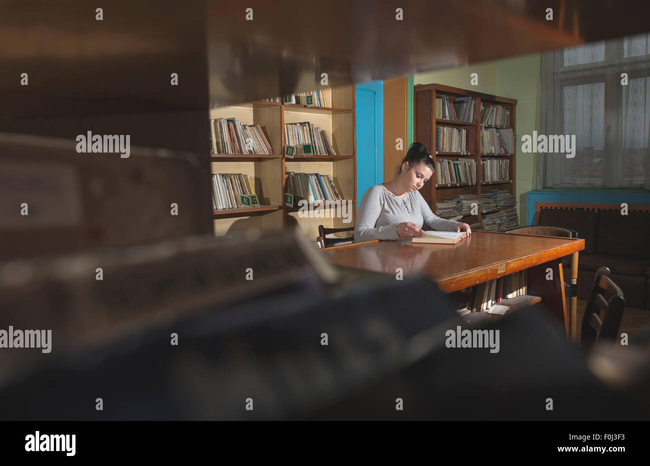 Studentin in einer Bibliothek. Blick auf Buch Stockfoto