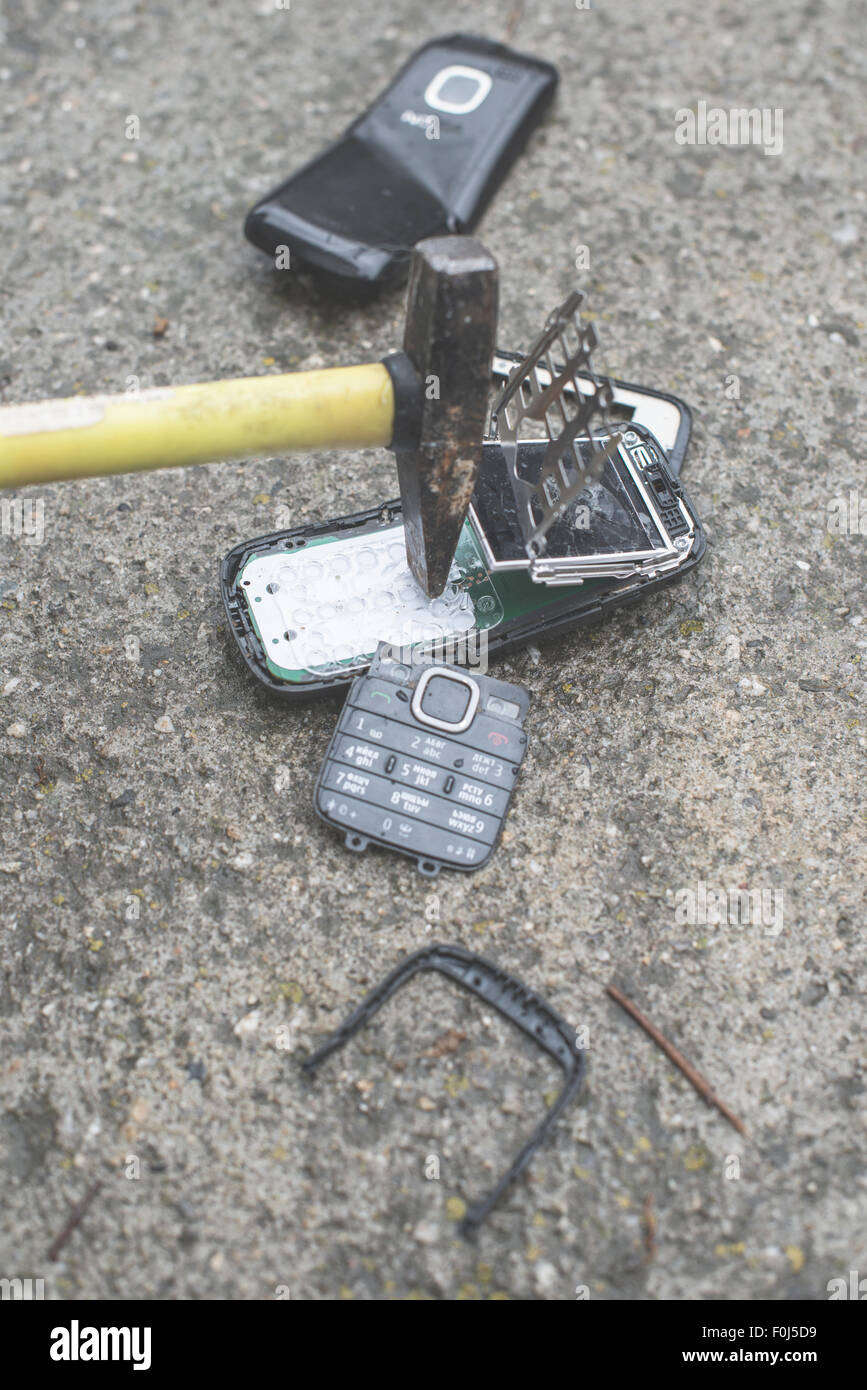 Altes Handy kaputt. Hammer-Falte-Telefon Stockfoto