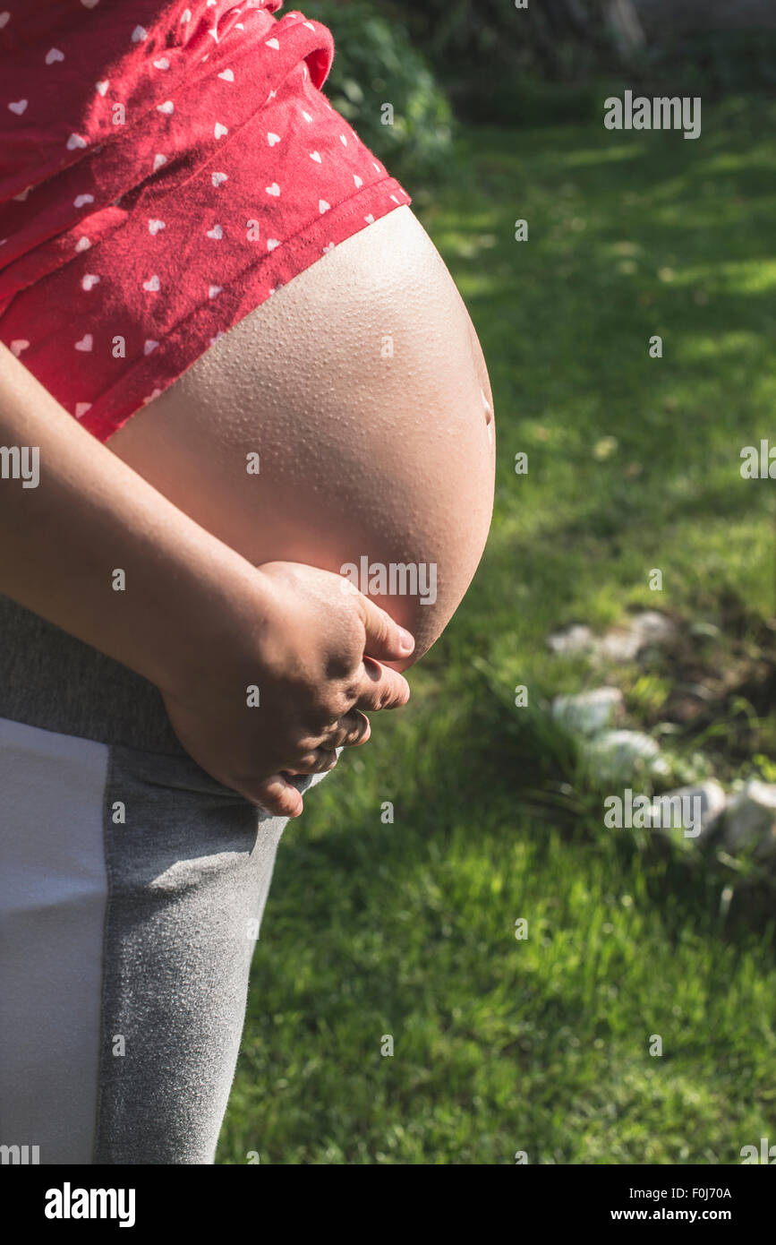 Schwangere Frau zeigt seinen Bauch. In der Natur. Grüne Wiese Stockfoto