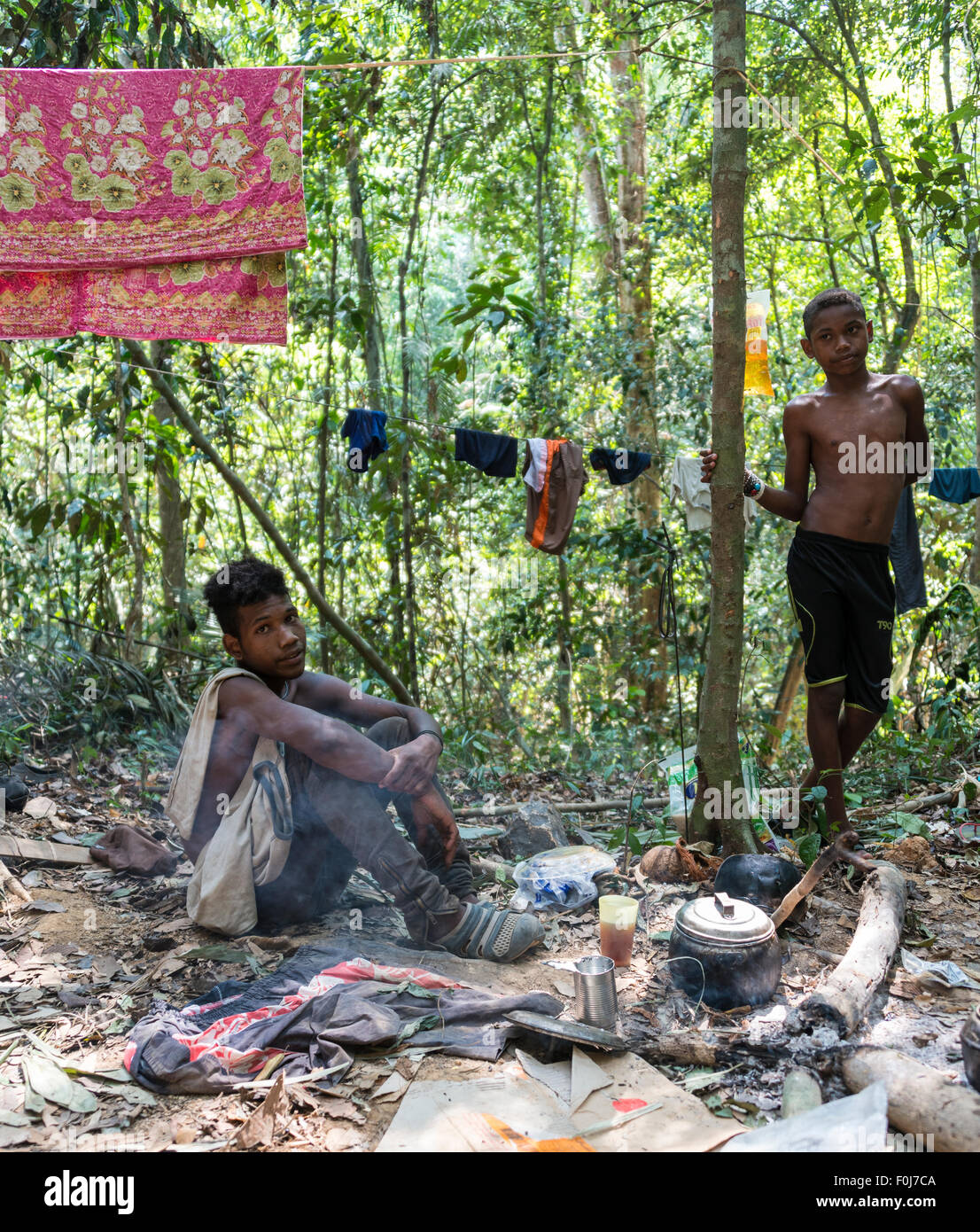 Zwei junge Männer des Stammes Orang Asil sitzen auf dem Boden in den Dschungel und machen Tee, native, indigene Völker Stockfoto