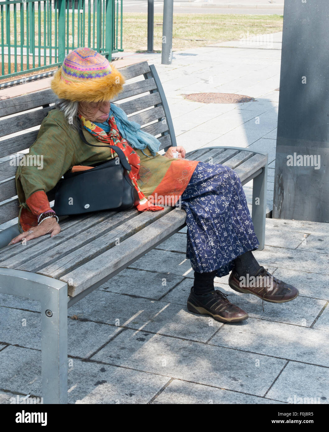 Coloufully gekleidete alte Dame schlafend auf einer Bank -1 Stockfoto
