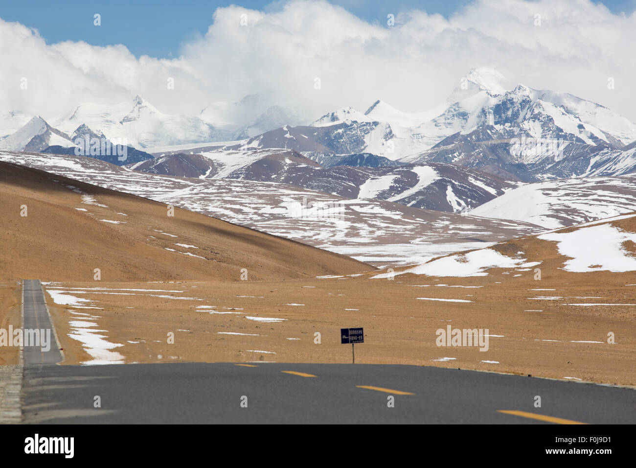 Gerade Straße mit einer gelben gepunkteten Linie in der Mitte mit tibetischen Landschaft der Berge im Hintergrund. Friendship Highway Stockfoto