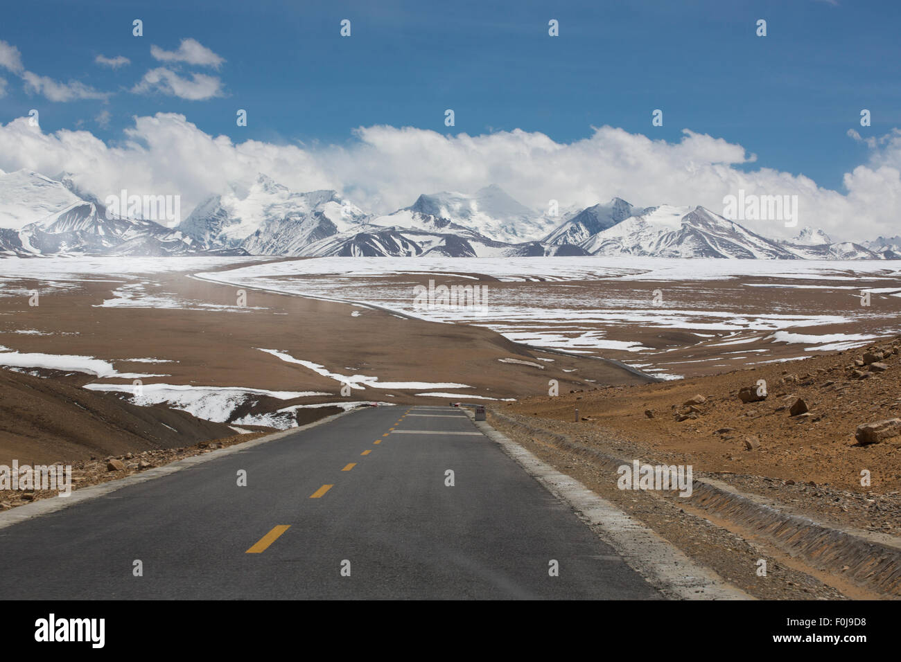 Gerade Straße mit einer gelben gepunkteten Linie in der Mitte mit tibetischen Landschaft der Berge im Hintergrund. Stockfoto