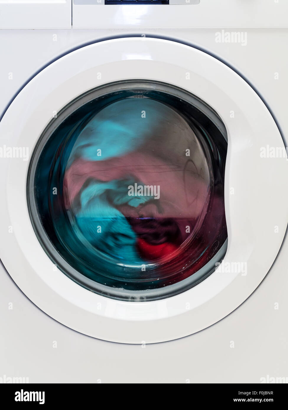 Nahaufnahme der Waschmaschine Tür mit spinning-Wäsche Stockfoto