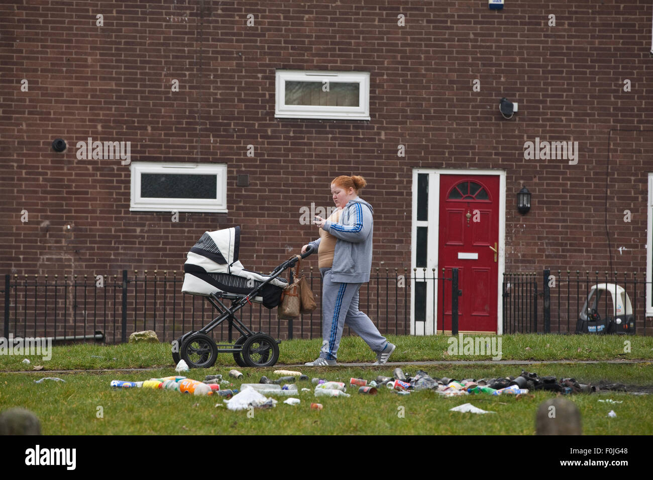 Eine Mutter schiebt ihren Kinderwagen durch die Armenviertel in zunächst, North East Manchester, England, Vereinigtes Königreich Stockfoto