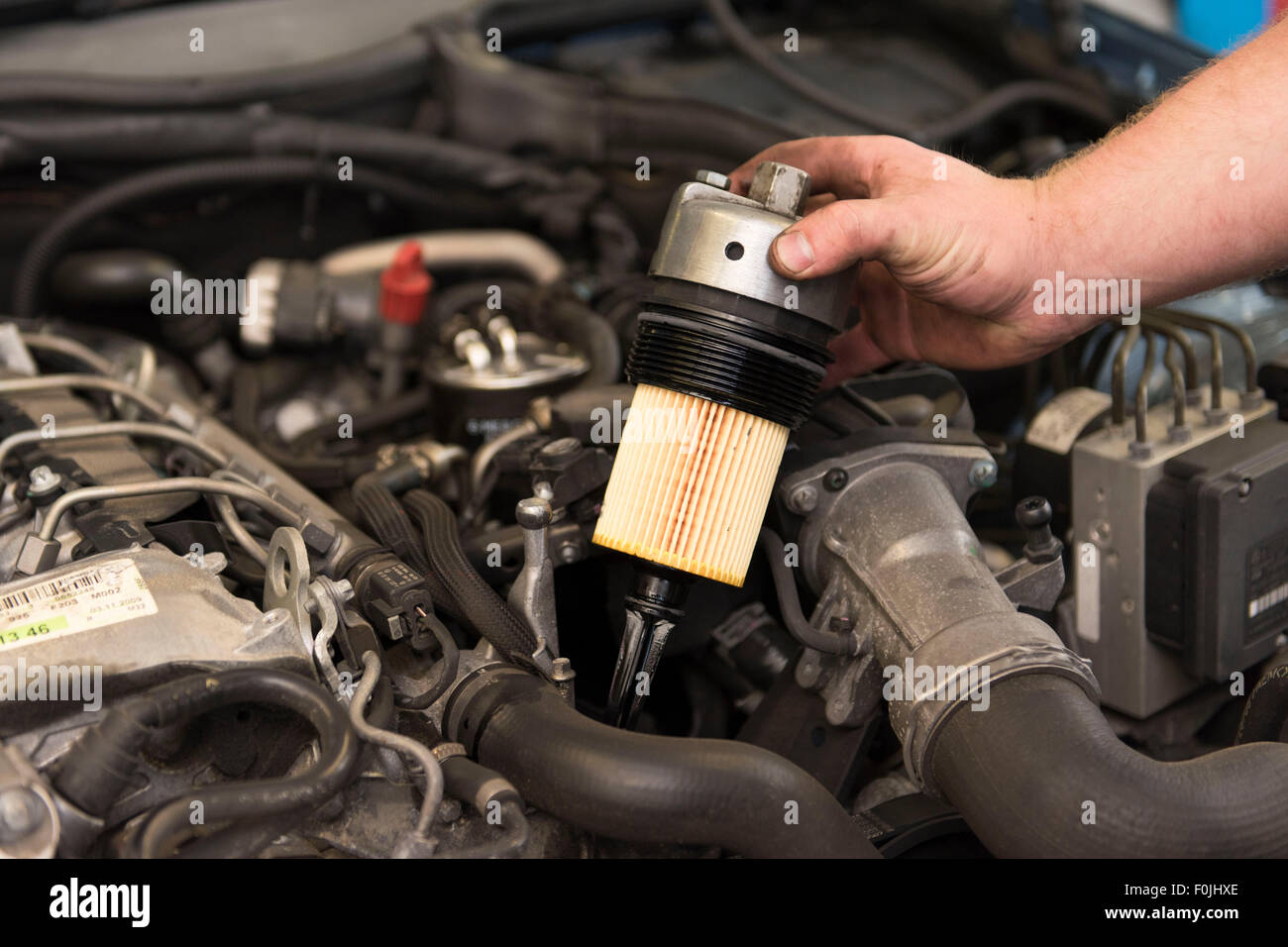 Kfz-Mechaniker passt einen Ölfilter zu einem Auto während der allgemeinen Wartung Stockfoto