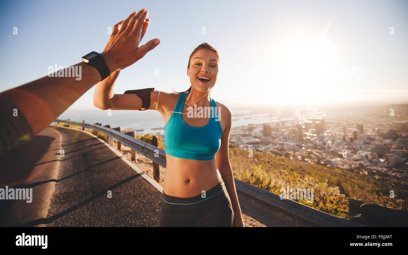 Passen Sie hohe Fiving junge Frau ihrem Freund nach einem Lauf. POV-Shot von Läufern auf Landstraße, die gerne im Freien mit hellen Su suchen Stockfoto