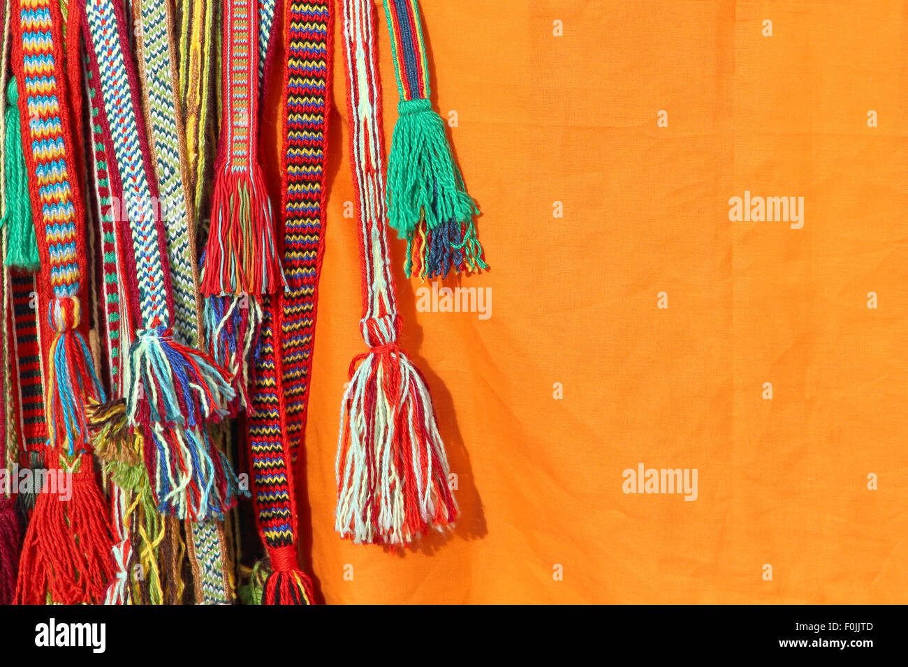 Farbenfrohe Quasten einer hippie Gürtel auf orangem Hintergrund. Stockfoto