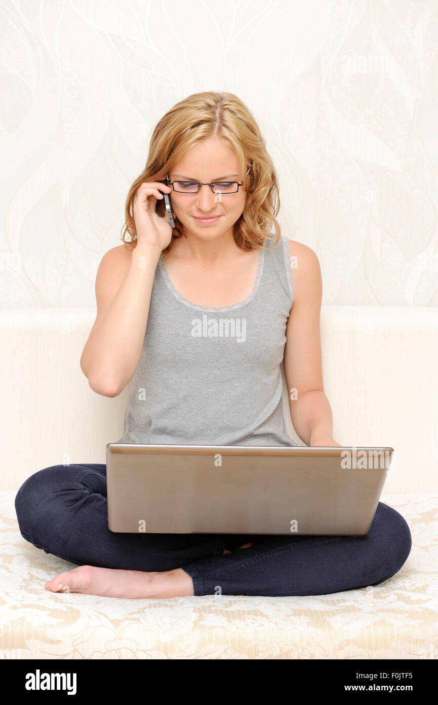 Junge Frau mit einem Laptop am Telefon sprechen Stockfoto