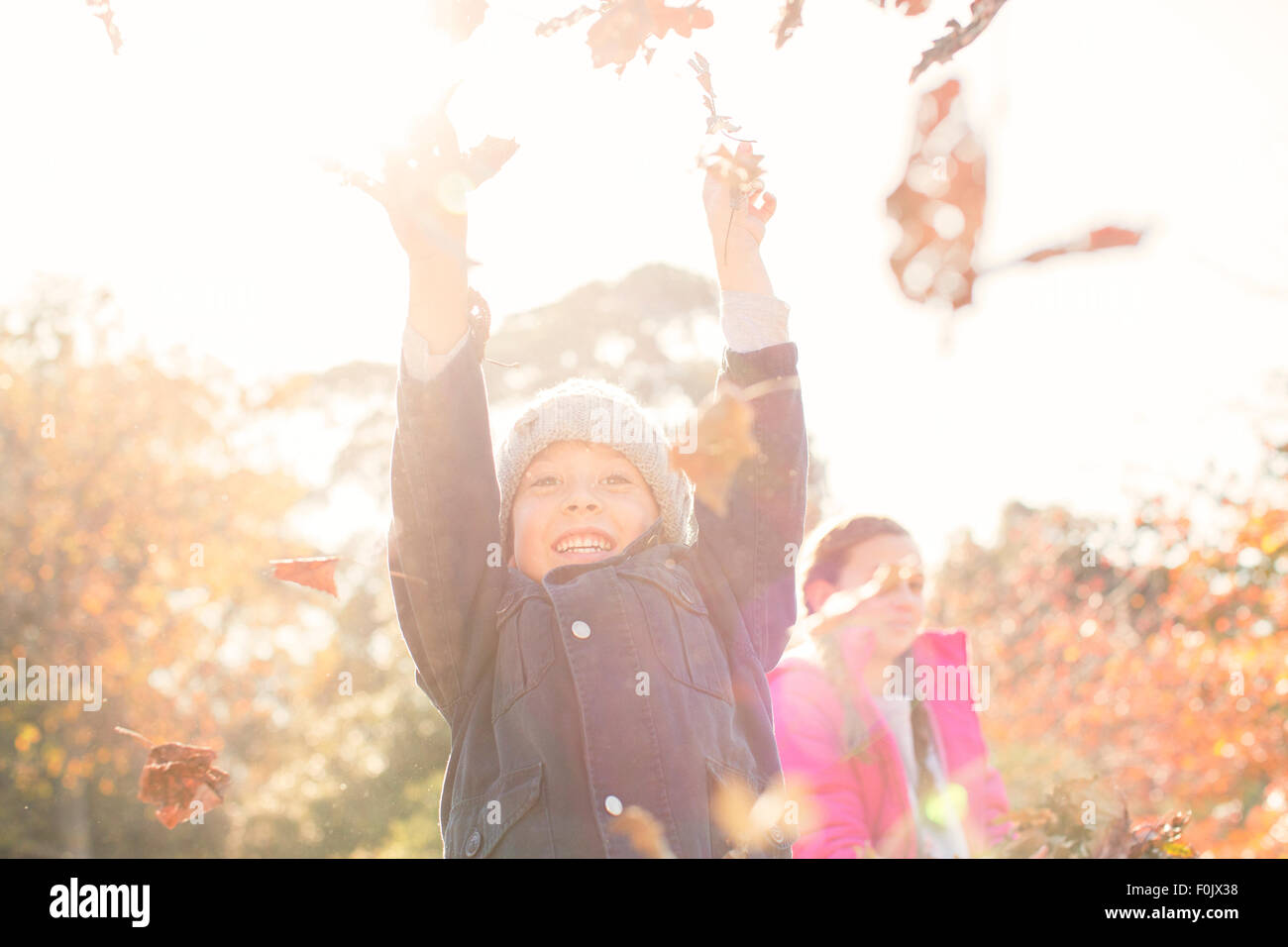Begeisterte junge spielt im Herbstlaub Stockfoto