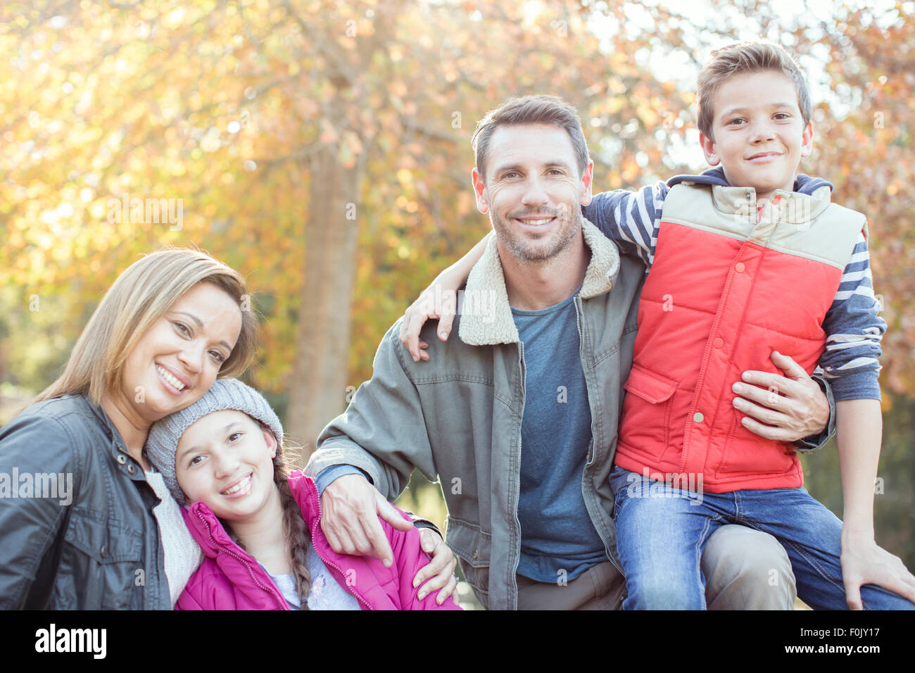 Lächelnde Familie Porträt vor Baum im Herbst Blätter Stockfoto