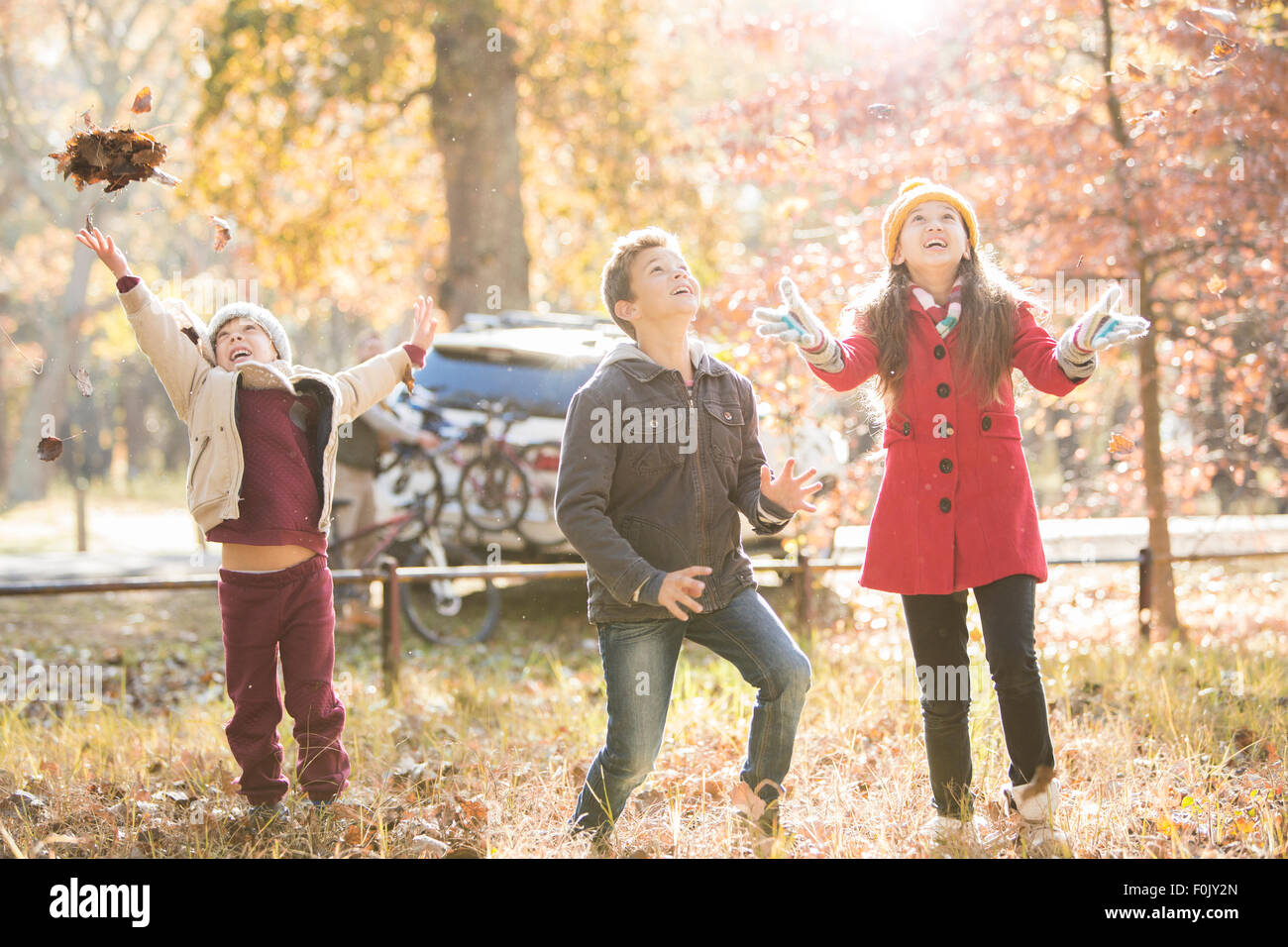 Jungen und Mädchen werfen Herbstlaub overhead im Wald Stockfoto