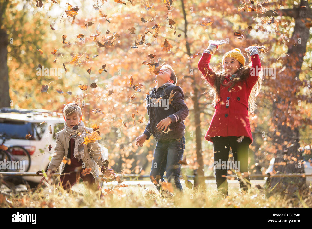 Jungen und Mädchen Herbstlaub über Kopf werfen Stockfoto