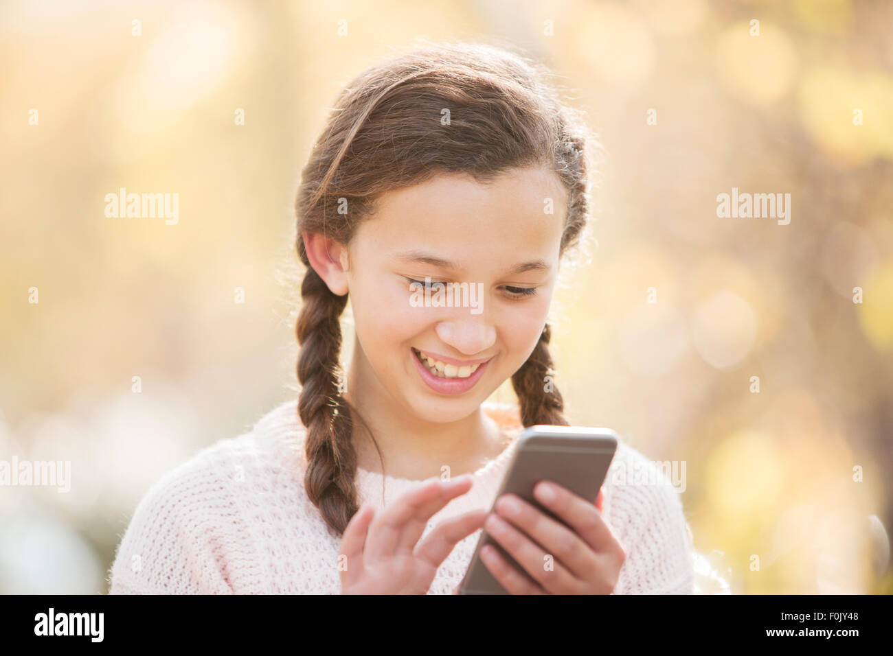 Lächelnde Mädchen SMS mit Handy-Natur hautnah Stockfoto