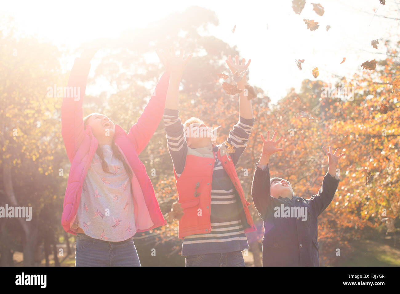 Jungen und Mädchen Herbstlaub über Kopf werfen Stockfoto