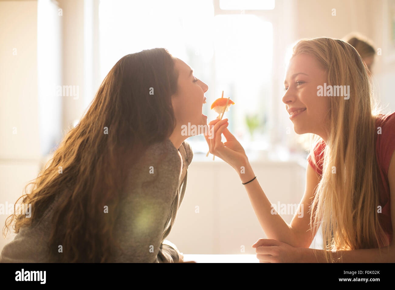 Teenager-Mädchen Freund Sushi mit Stäbchen zu füttern Stockfoto