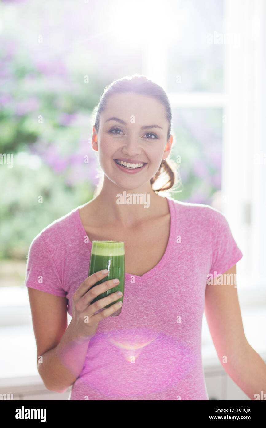 Porträt lächelnde Frau trinken grünen smoothie Stockfoto